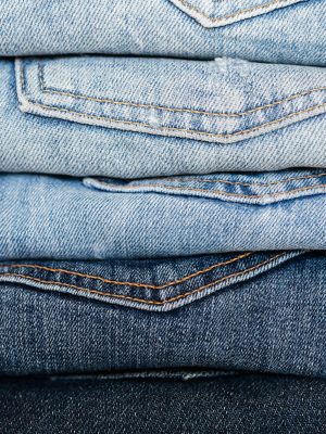 Closeup of stack of blue denim pants neatly arranged according to color from lightest to darkest